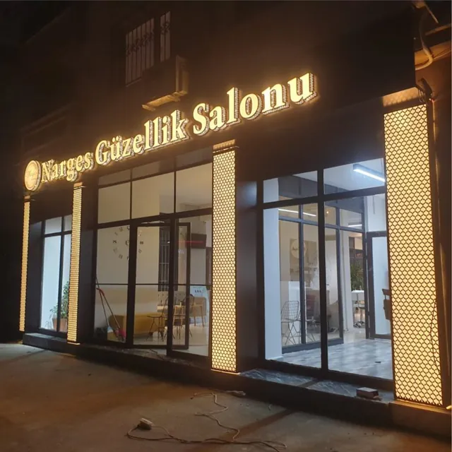 Güzellik salonu girişinde ışıklı gold krom kutu harf, gece