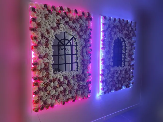 Çiçek duvarı çevresinde mavi ve pembe neon çerçeve